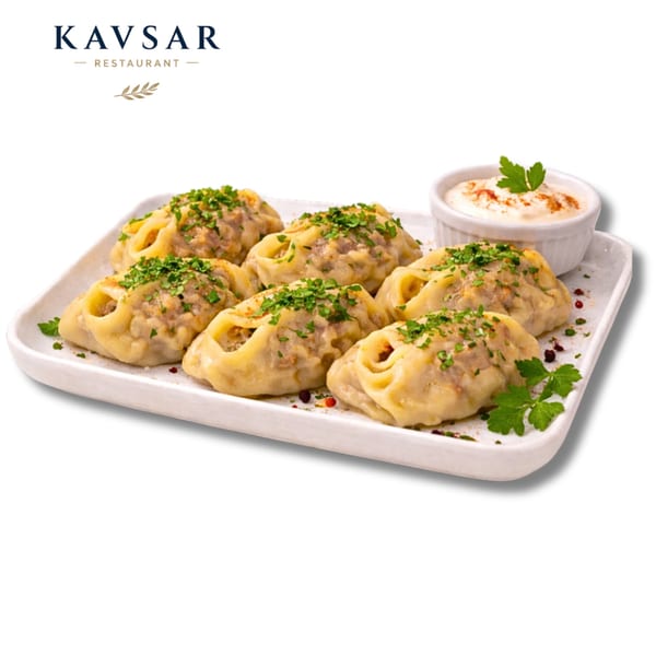 Six Kavsar Restaurant manti dumplings with herbs and a side of white sauce on a white plate.