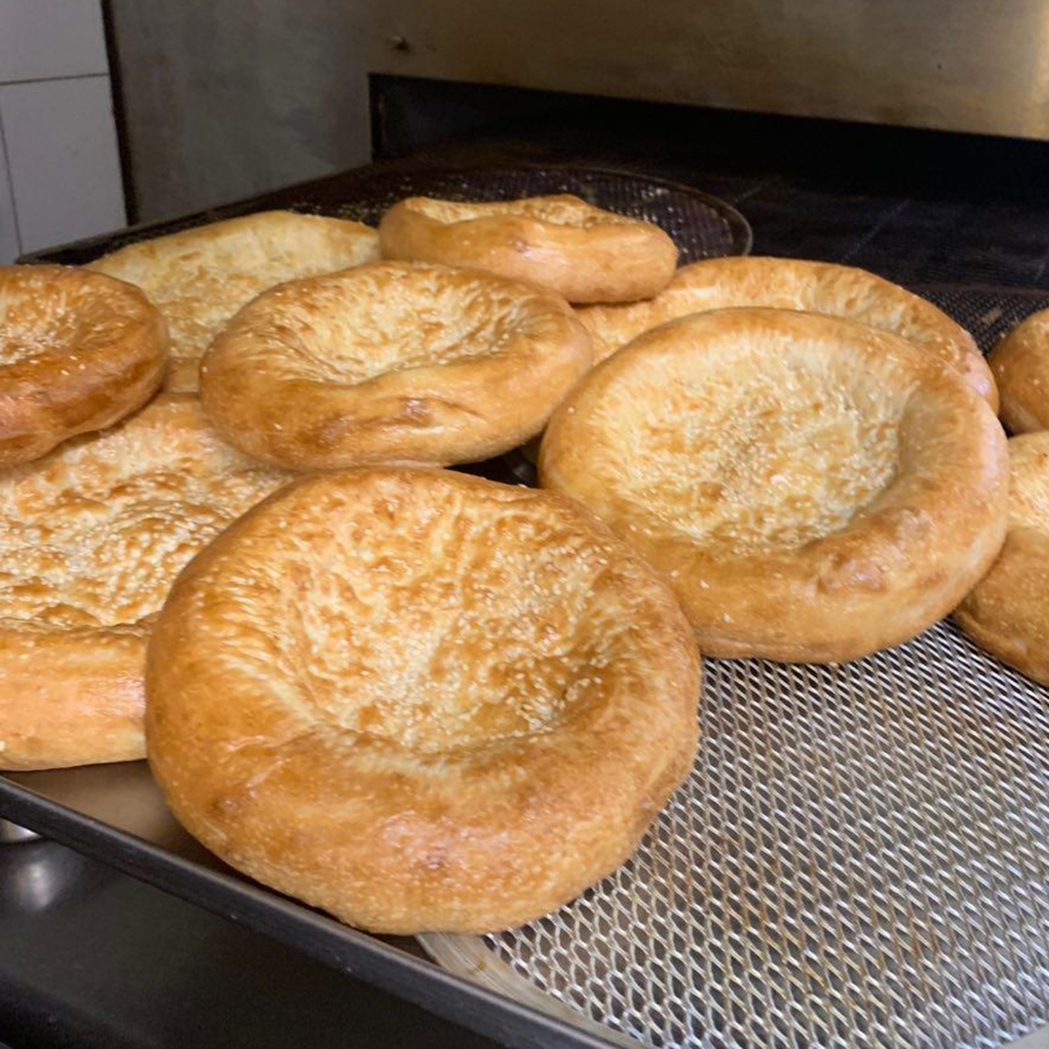 Freshly baked golden round breads cooling on a wire rack inside a commercial oven.