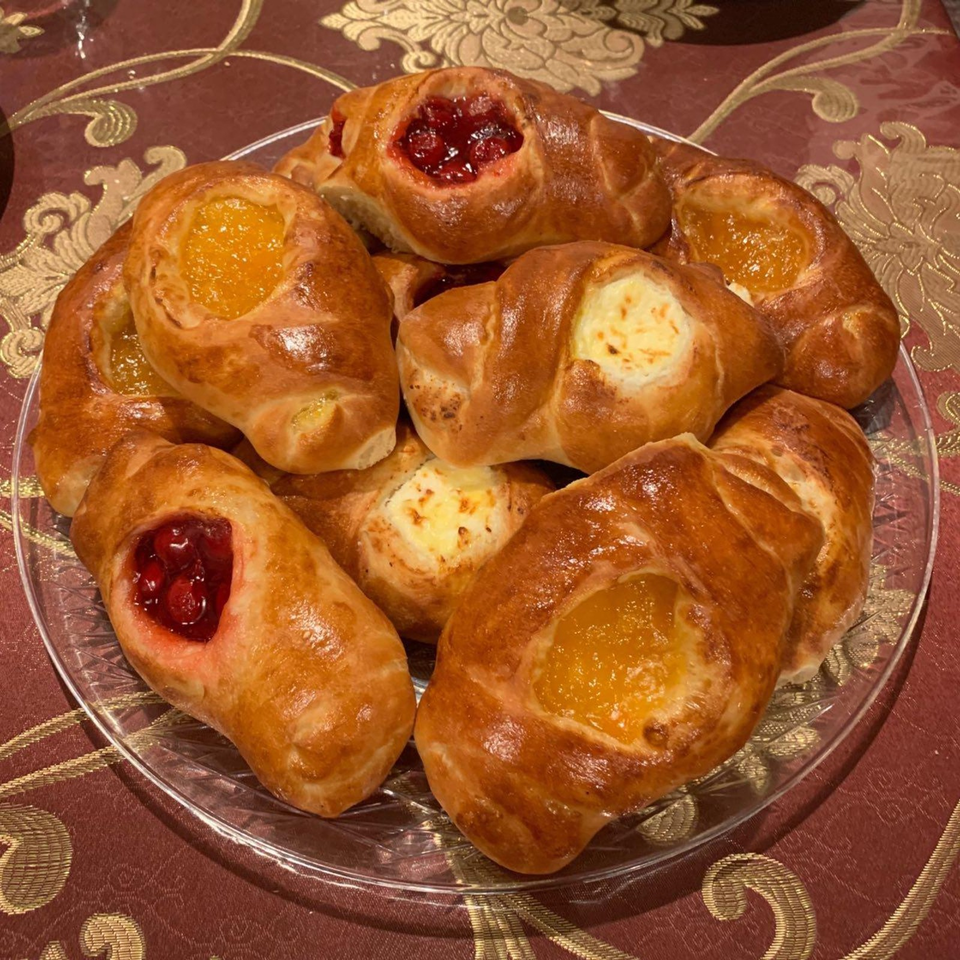 Golden-brown pastries filled with cherry, apricot, and creamy cheese fillings arranged on a glass platter.